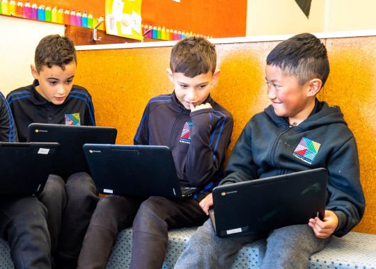 Three children working on laptops.